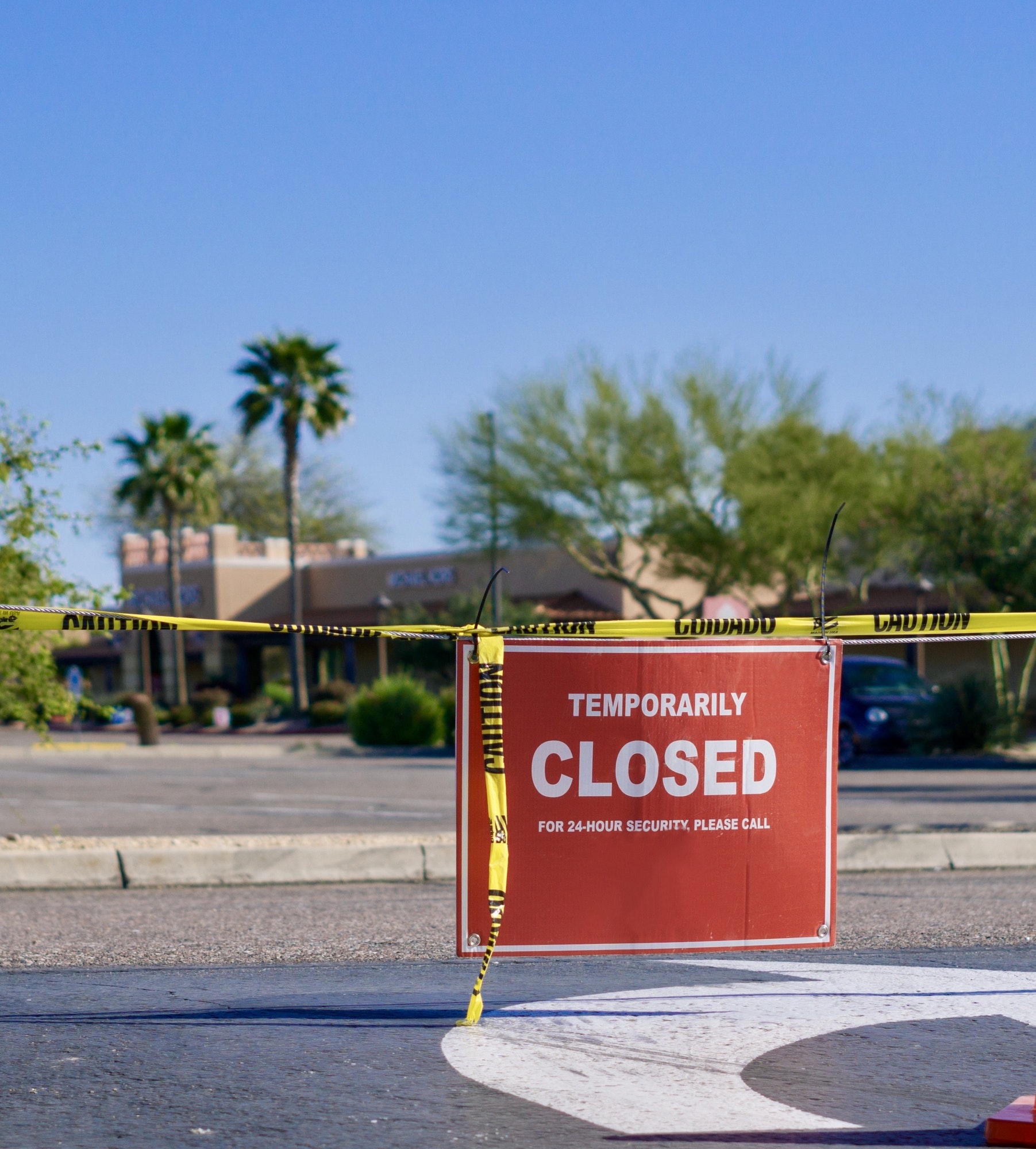 Temporarily closed sign on yellow caution tape in front of a shopping center